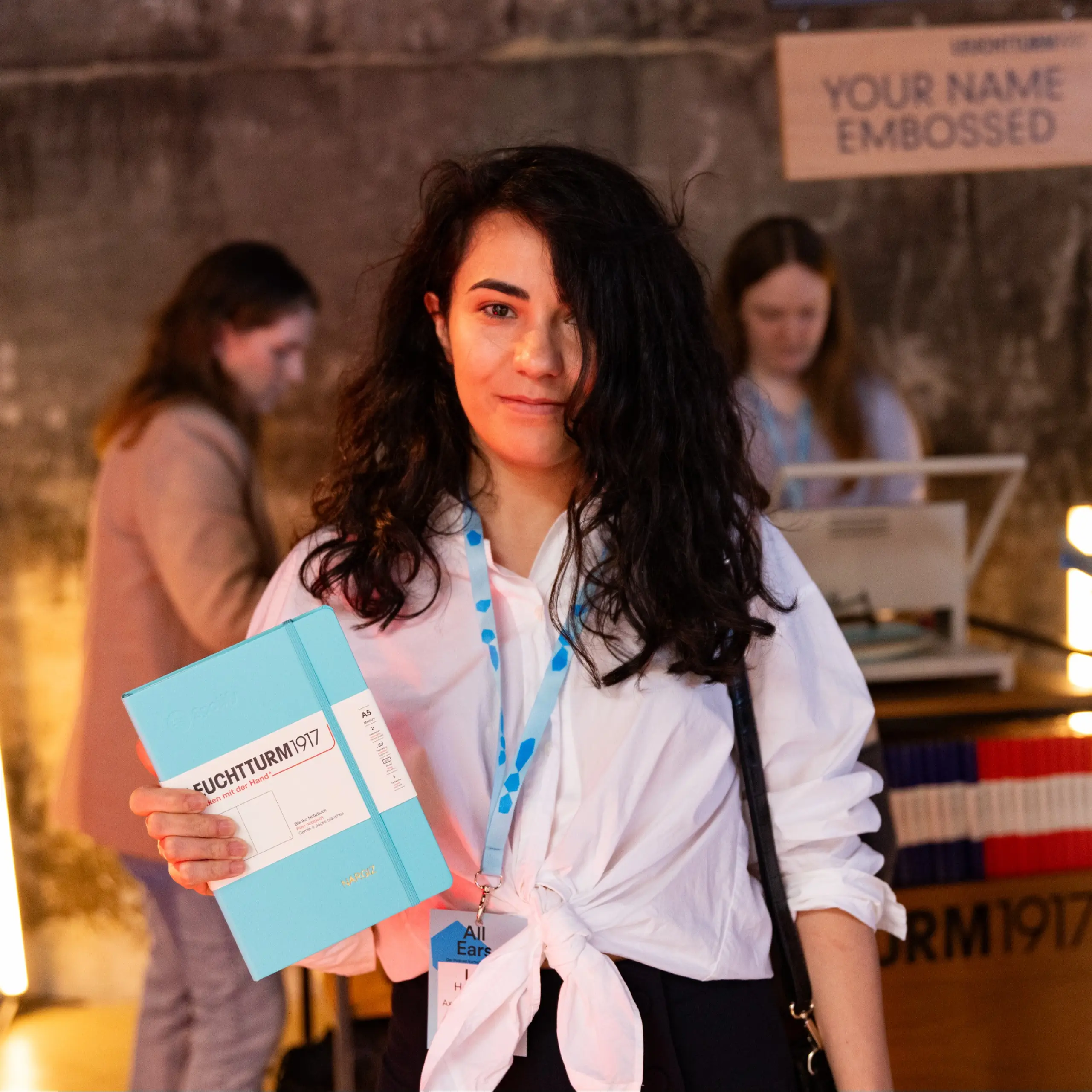 Leuchtturm1917 bei Spotify All Ears: individuelle Namensprägung. Persona sostiene una libreta LEUCHTTURM1917 turquesa con grabado de nombre.